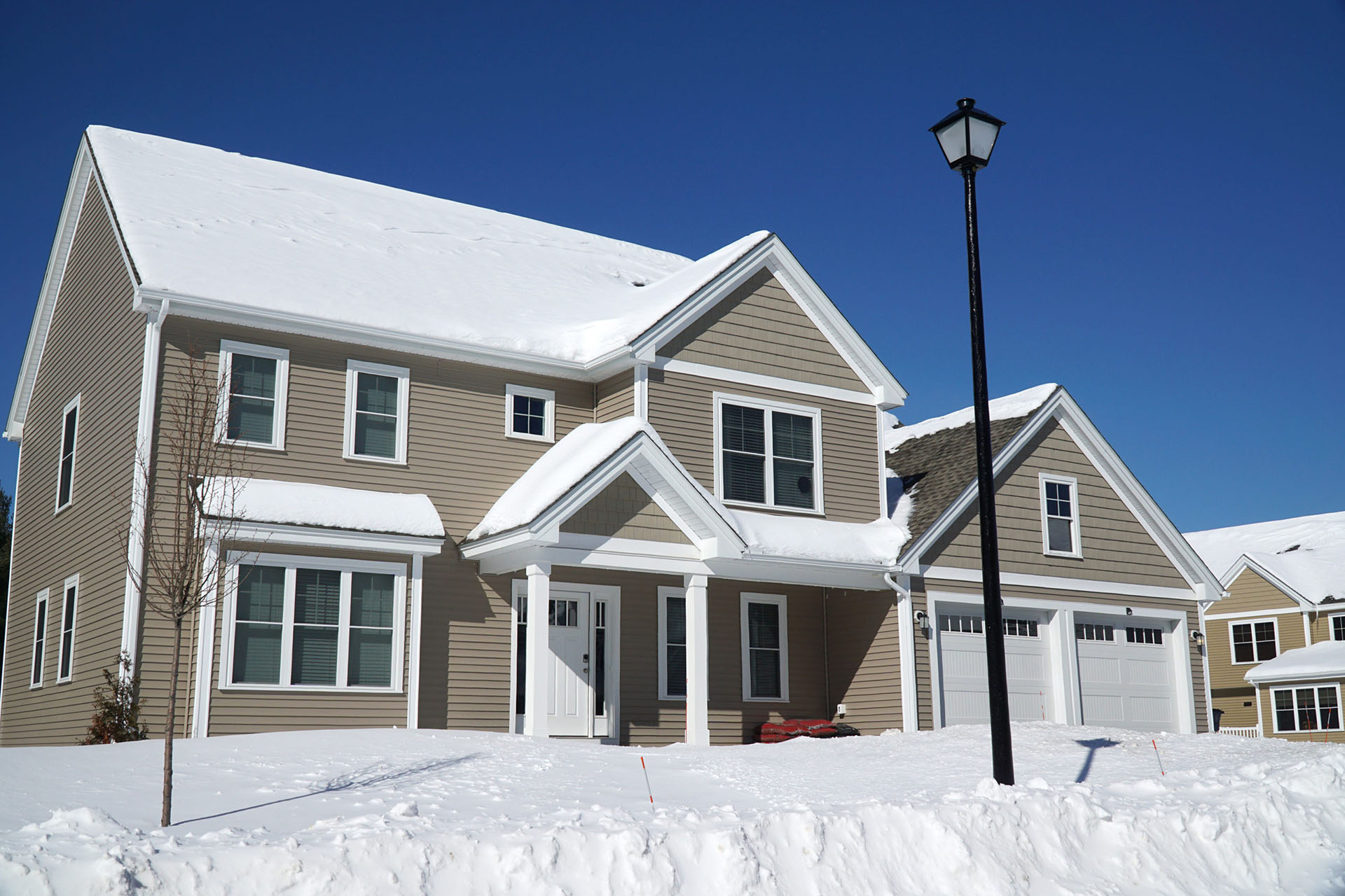 Snow-covered home with tan siding